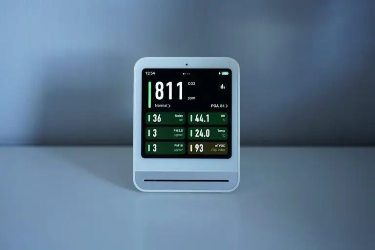 indoor air quality monitor displaying CO2 and humidity readings on desk